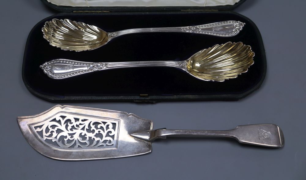 A cased pair of fancy silver serving spoons by George Adams, London, 1857 and a silver fish slice
